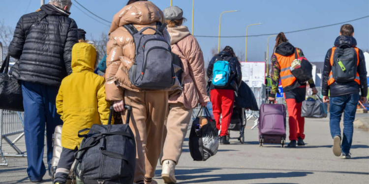 Grupo de personas caminando con equipaje hacia un centro de retorno